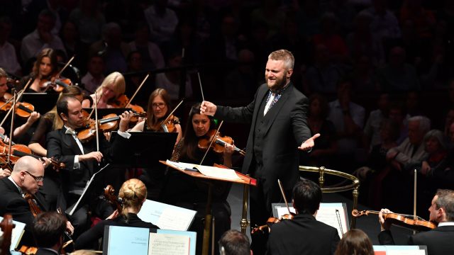 Kirill Karabits has his arms spread and a wide smile as he conducts the BSO.
