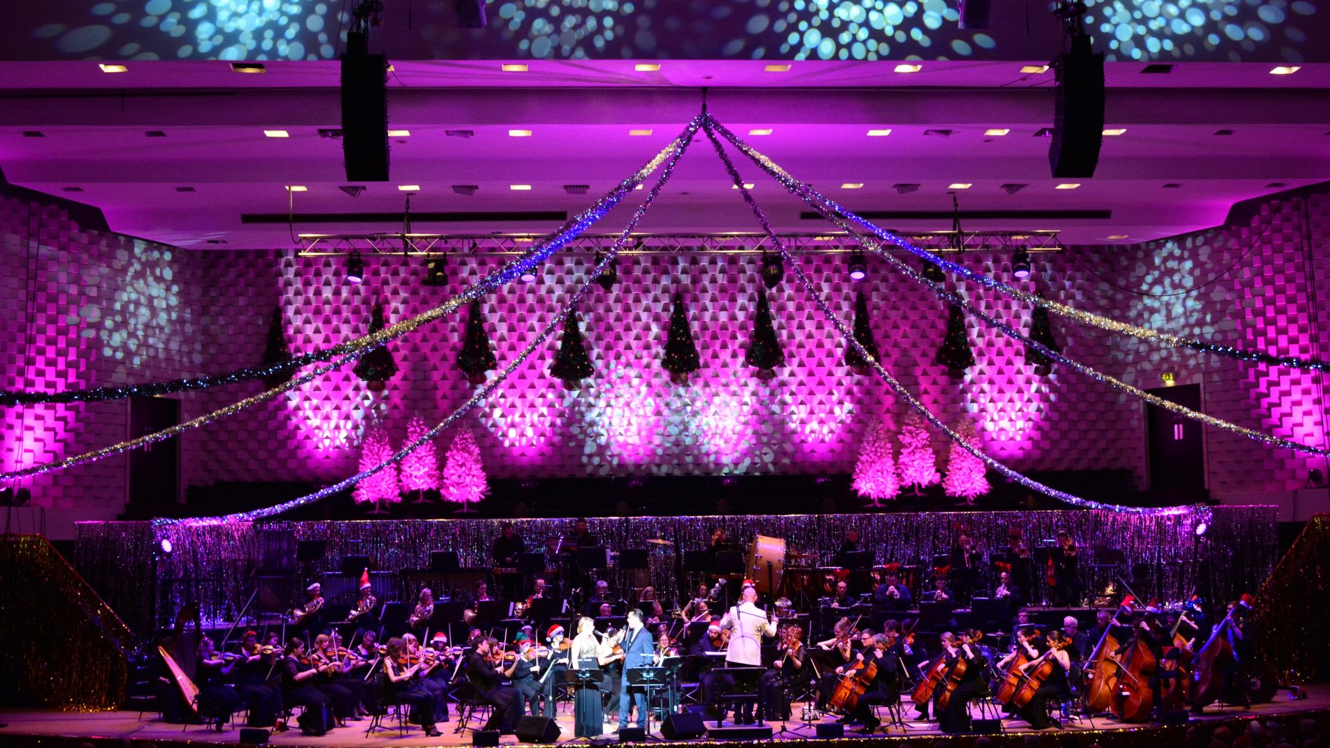 A full symphony orchestra on the stage with festive decorations