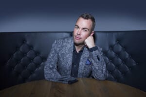 Nicholas McCarthy sits at a table in a blue suit