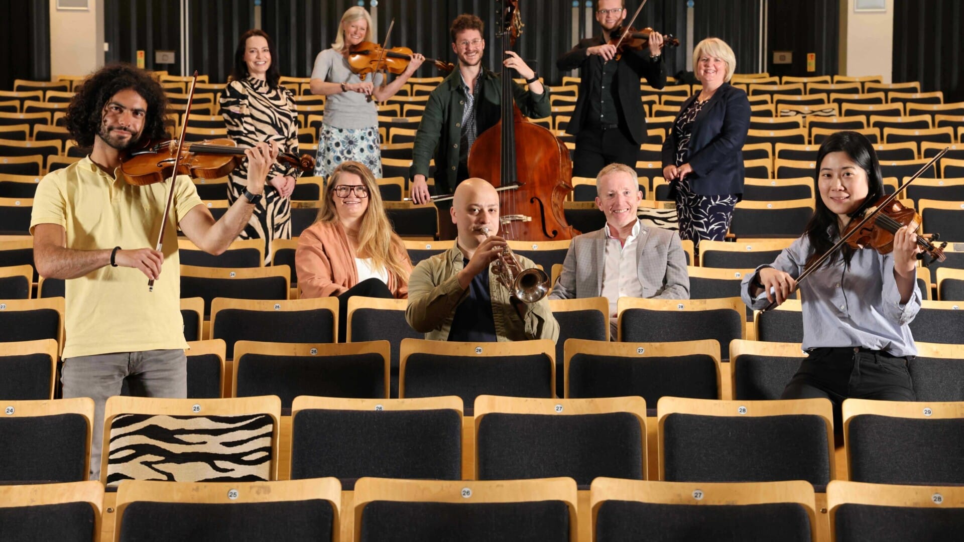 Musicians and staff of Bournemouth Symphony Orchestra sit with Solicitors from Ellis Jones solicitors in seats in Lighthouse Poole auditorium