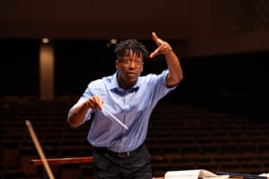 Enyi Okpara conducts the BSO wearing a blue shirt