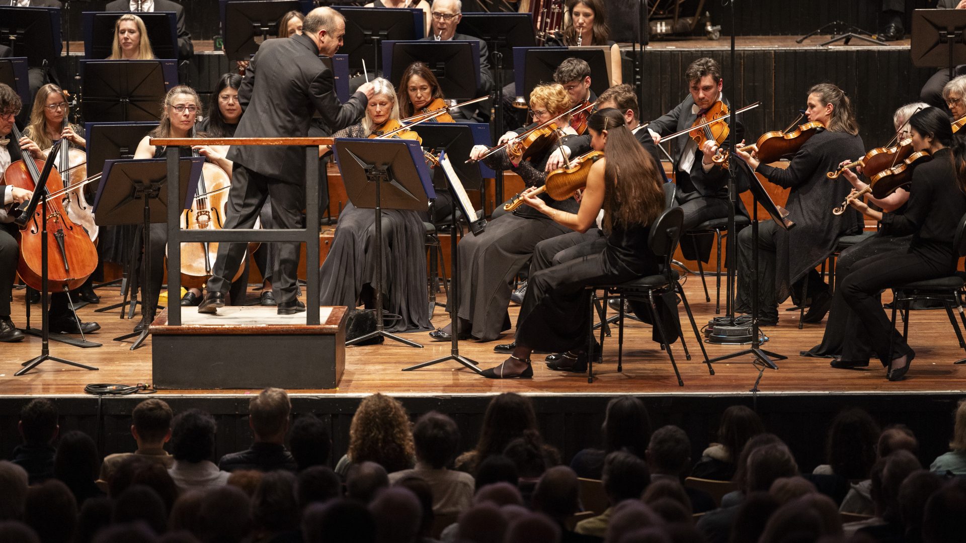a wide angle shot of BSO Chief Conductor, Mark Wigglesworth conducting the Orchestra during a concert.
