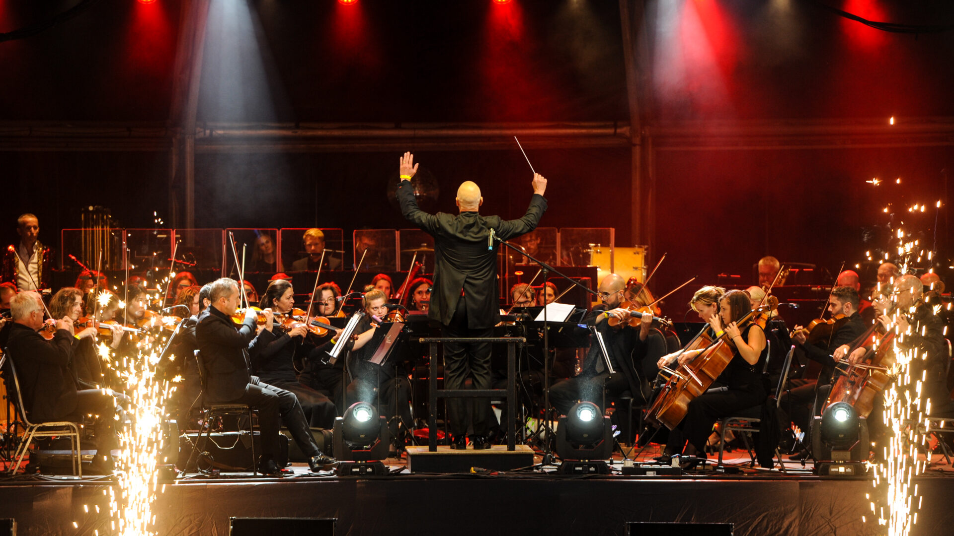 Orchestra performing on a live outdoor stage.