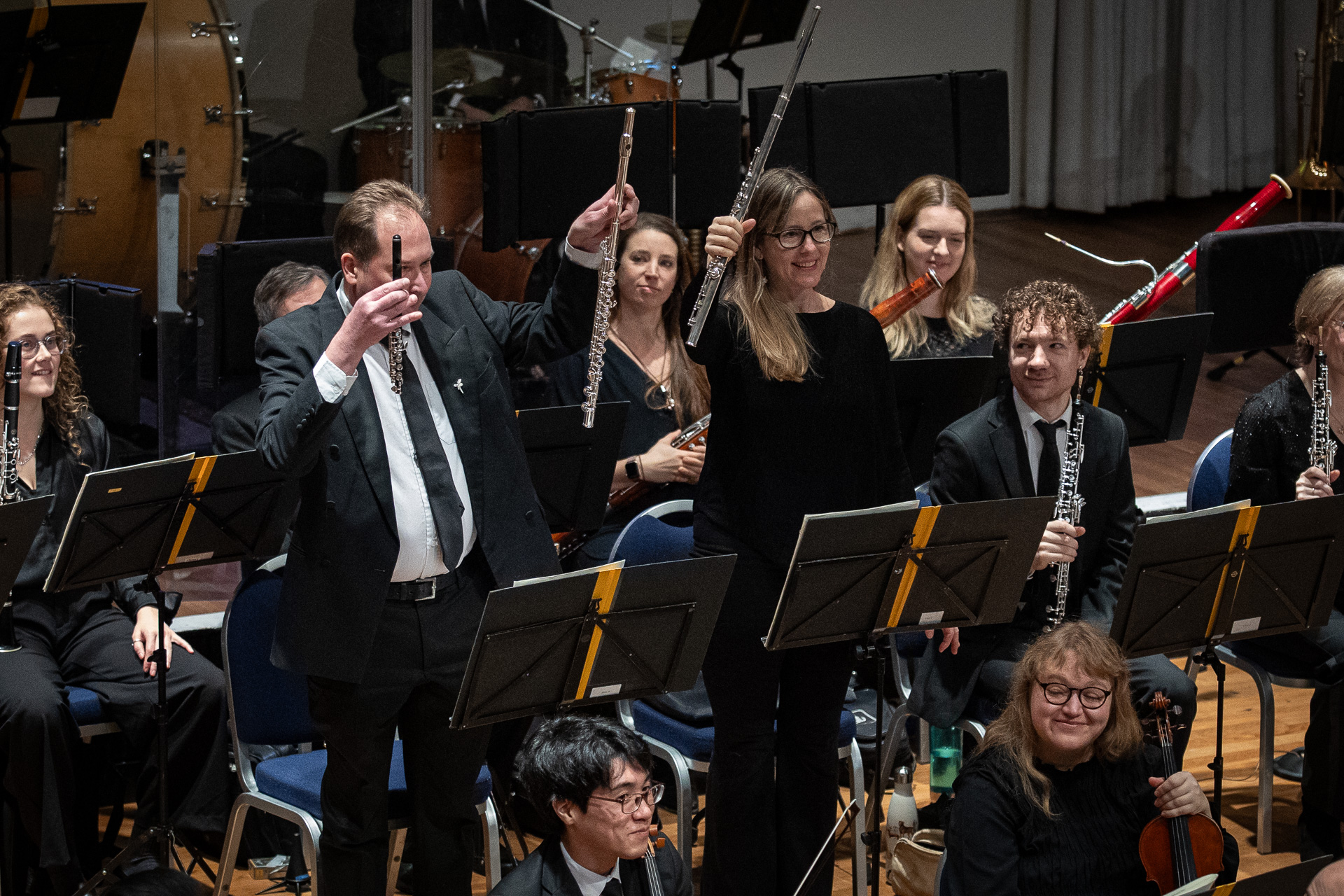 Two musicians hold up their instruments for an audience of children to see