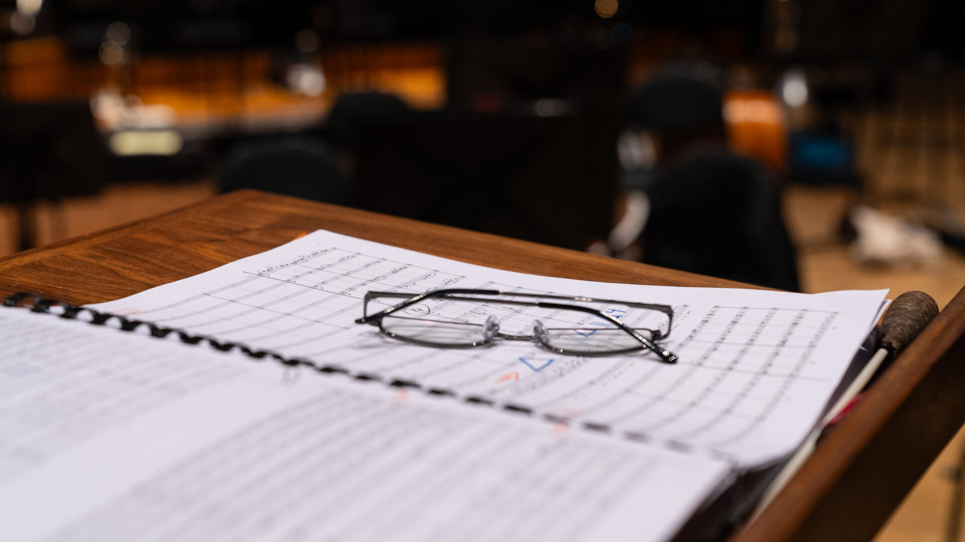 A musical score lays open on a music stand with glasses on top.