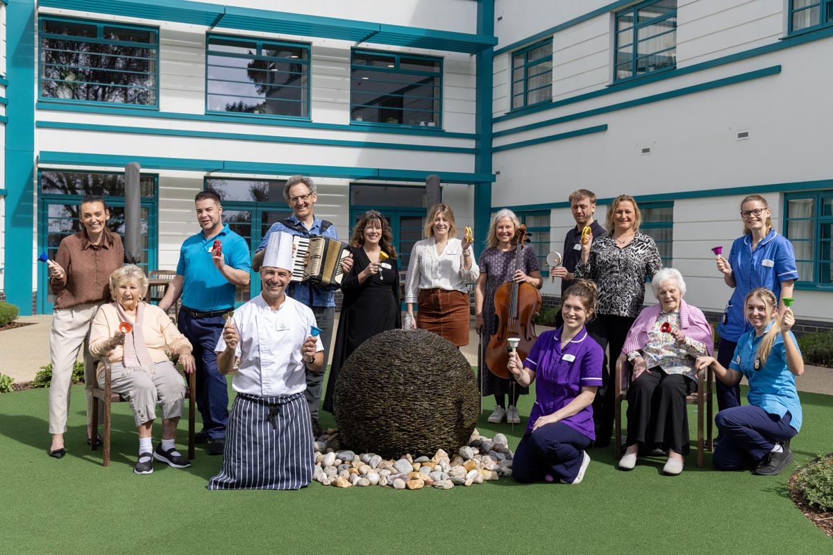 Group of care home residents and staff pose for a group photo with BSO musicians at Marjorie House