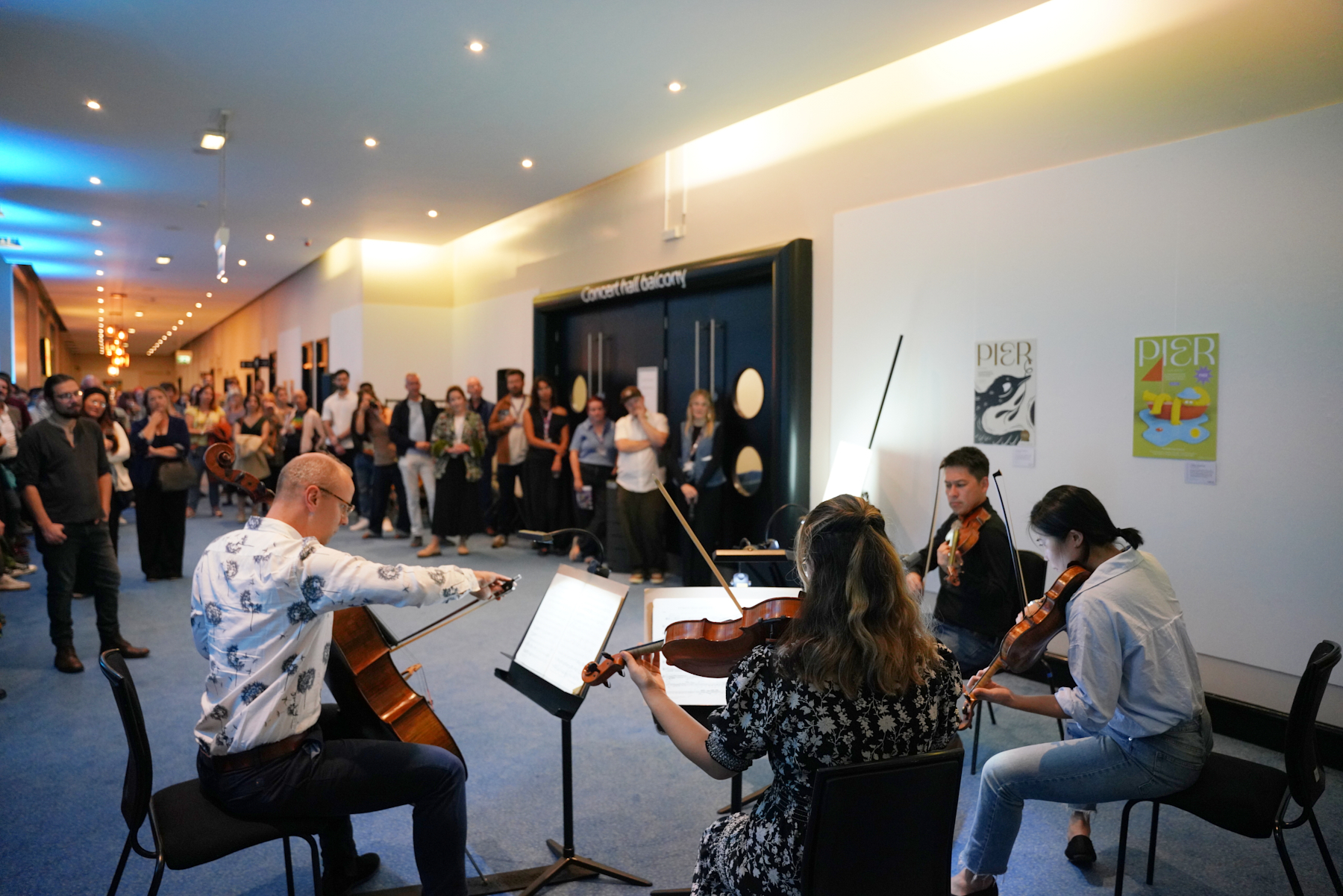 A quartet of musicians performs to a standing audience